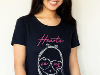 A girl laughing wearing the Dancing Hearts Lolligag Tee